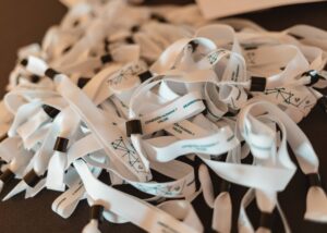 Una pila de cordones blancos con clips negros, impresos con texto y diseños geométricos, colocados sobre una mesa.