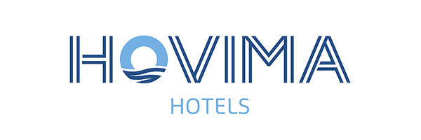 Logotipo de Hovima Hotels con la palabra "Hovima" en letras mayúsculas de color azul y un diseño abstracto de un sol y olas en la letra "O". La palabra "Hoteles" aparece debajo en letras más pequeñas de color azul claro. El logo rinde homenaje a la feria de empleo 2019.