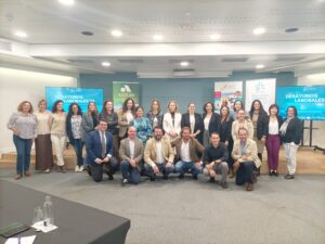 Un grupo de personas posando para una foto en una sala de conferencias, con pancartas de presentación en el fondo.