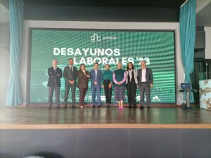 Un grupo de ocho personas frente a una gran pantalla que muestra el texto "Desayunos Laborales '23.