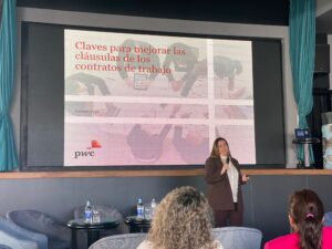 Persona que presenta una diapositiva titulada "Claves para mejorar las cláusulas de los contratos de trabajo" con el logo de PwC. Público sentado en primer plano.