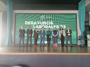 Siete personas se encuentran frente a una gran pantalla en la que está escrito "Desayunos Laborales '23".