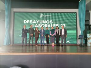 Un grupo de personas se encuentra en el escenario frente a una pantalla de presentación verde donde se muestra el texto "Desayunos Laborales '23.