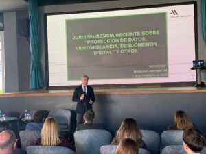 Una persona da una presentación sobre los últimos avances legales en protección de datos, videovigilancia, desconexión digital y otros temas a una audiencia en una sala de conferencias.