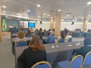 Un grupo de personas sentadas en una sala de conferencias escuchando una presentación.