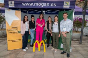 Grupo de personas frente a una carpa con el logotipo de McDonald's y pancartas promocionales.