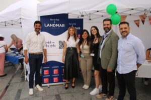 Un grupo de seis personas de pie delante de un stand con un cartel que dice "Landmar Hotels", sonríen y posan para la foto.
