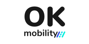 La imagen muestra el logotipo de OK Mobility, con "OK" en letras negras grandes encima de la palabra "mobility" en letras más pequeñas. Hay tres líneas diagonales azules y verde azulado a la derecha de la palabra "movilidad", lo que promueve su participación en Job Dating 2023.